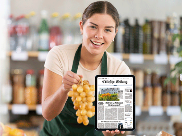 Darf's ein wenig mehr sein? Frau mit Weintrauben in der rechten Hand und in der linken Hand ein Tablet mit dem E-Paper der Celleschen Zeitung.