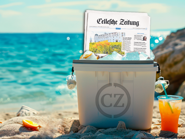 Kühlbox am Strand mit der gedruckten CZ, daneben im Sand steht ein oranges Kaltgetränk